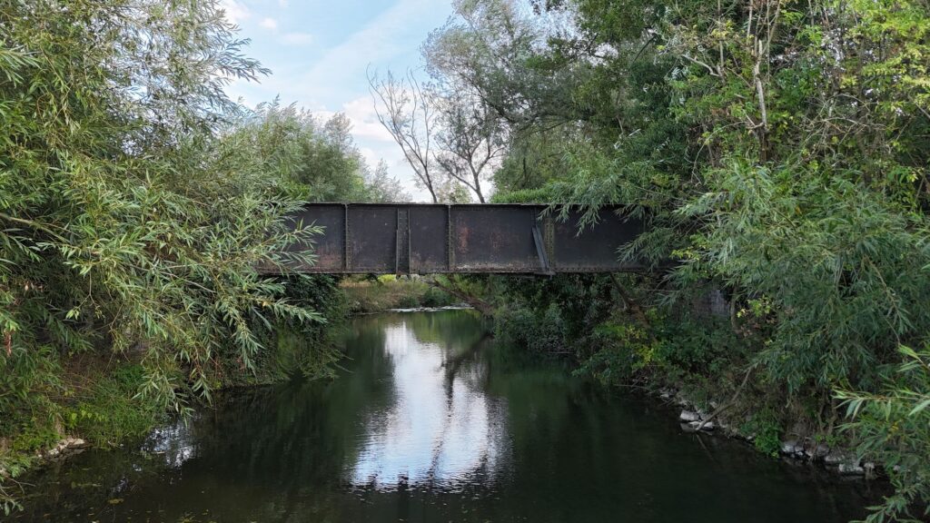 Aston Cantlow railway bridge crossing the River Alne, framed by trees and riverside vegetation